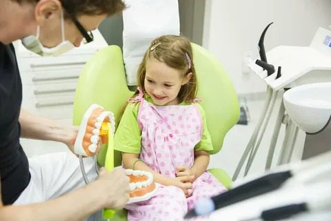 Pediatric dentist teaching a child proper brushing technique at dental office in Parker, CO